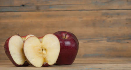 A composition of red apples, cut and whole, on a wood background. natural fruits. The half of apple. Space for your text.の写真素材