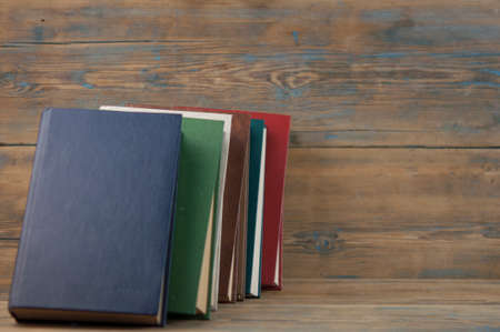 Many stacked books on wooden background. Back to school with copy space.の写真素材