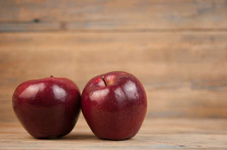 Two Bright Red and Ready to eat Apple in Rustic Barn Setting with Old Wood Boards and room or space for copy, text, your words.の写真素材