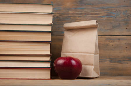 stack of books with red apple, lunch bag on the wood table with copyspaceの写真素材