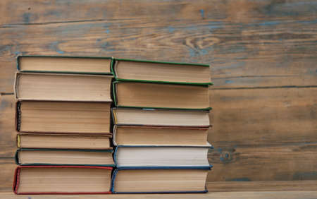 Many stacked books on wooden background. Back to school with copy space.の写真素材
