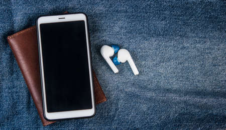 Smartphone, earphone and brown leather wallet on blue shabby jeans hipster modern life style layout for inserting textの写真素材