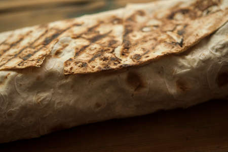 The process of cooking chicken wrap on kitchen table at home concept. Homemade kebab close up. Fresh thin lavash or pita bread roll of shawarma sandwich with ingredients inside.の写真素材