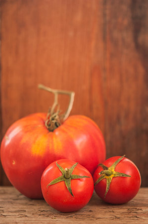 whole tomatoes on brown textured woodの写真素材