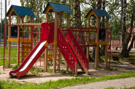 Colorful children playground activities in public park surrounded by green trees