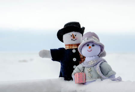 cute snowman couple at a wintery beachの写真素材
