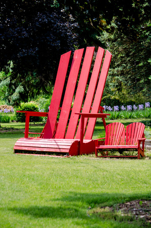 The chairs on the right are normal typical Adirondack chairs, the one on the left is a mega chair, about 10 foot tallの写真素材