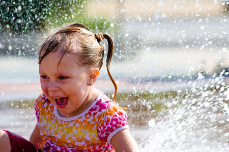 Happiness is a wet city fountain on a hot summer day, as this laughing little girl shows の写真素材
