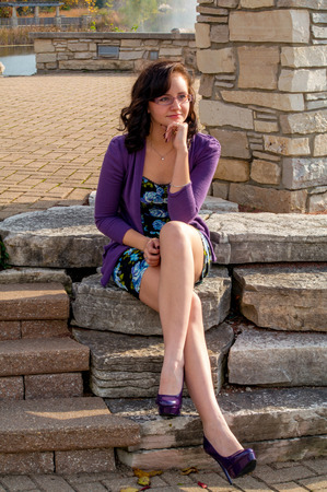 a teen girl with purple shoes sits on a rocky stepの写真素材