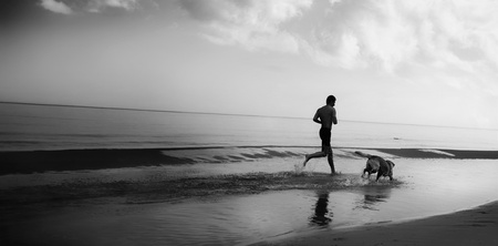 A man running with a dog on the seashoreの写真素材