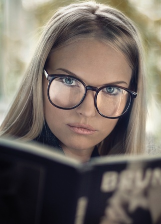 Young girl in glasses reading a bookの写真素材