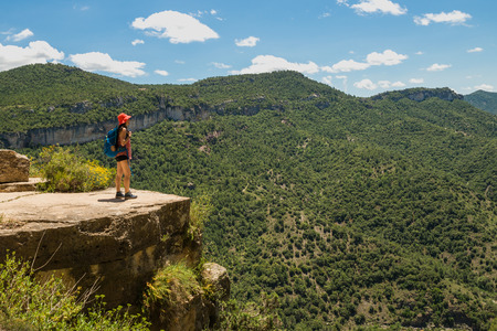 Hiker girl watching the beautiful view from the top of a cliff