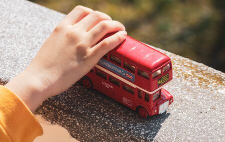 Hand of Small Child Playing with a Red Double-decker Bus Toyの写真素材
