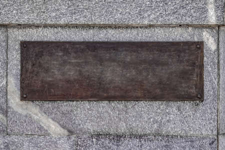 Blank template brown bronze plaque on gray granite wall. Vintage background with copy space of the...