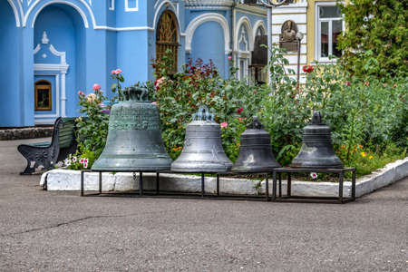 Kharkiv, Ukraine - July 20, 2020: Four church bells stand on a pedestal in the courtyard of Pokrovsky Monastery in Kharkov. Exhibition of bells against the background of a summer flower bed outdoorsのeditorial素材