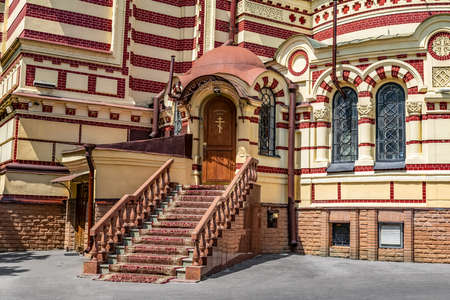 Kharkiv, Ukraine - July 20, 2020: Service entrance to the Annunciation Cathedral in Kharkiv. Red and beige striped facade of an Orthodox church closeupのeditorial素材
