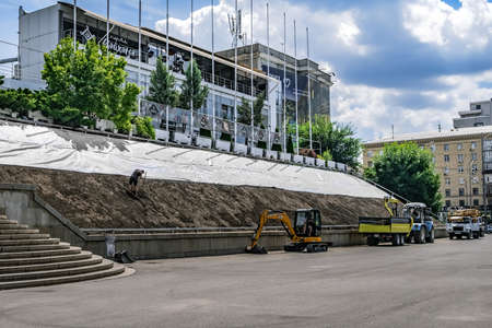 Kharkiv, Ukraine - July 20, 2020: Slope greening work on a city street in Kharkov. Worker is engaged...