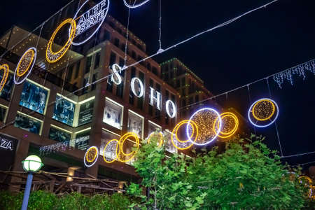 Dnipro, Ukraine - July 20, 2020: Night festive illumination on Katerynoslavsky Boulevard in Dnipro. Glowing round signs of Soho and Alef Estate against the background of dark buildings and black skyのeditorial素材