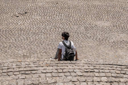 Aerial view to male tourist with a backpack rests on the stone steps against the background of a...