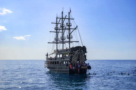Turkey, Alanya - October 22, 2020: Vintage pirate ship and tourists swimming in the water near it in the Mediterranean in Alanya. Old three-masted schooner against the background of the sea horizonのeditorial素材