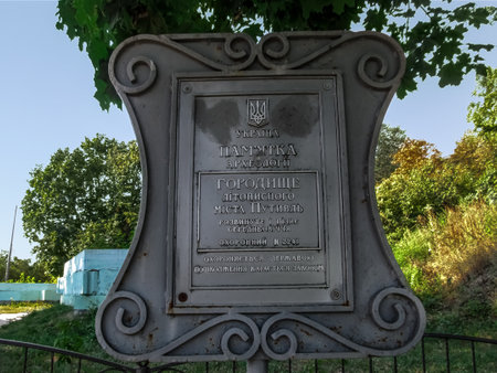 Putyvl, Ukraine - August 18, 2018: Signboard Settlement of the chronicle town of Putyvl, close-up (Sumy region). Bronze decorative vintage information plate at the entrance to Putivl city parkのeditorial素材