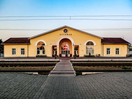 The building of the Putyvl Train Station in Buryn (Sumy region, Ukraine) on an early summer morning. Peron and railway tracks on the background of the yellow station buildingのeditorial素材