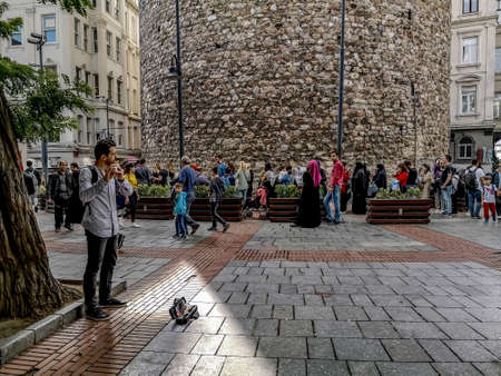 Istanbul, Turkey - October 29, 2019: A street musician in front of a queue of tourists at the Galata Tower in Istanbul. Many people in the old historic squareのeditorial素材