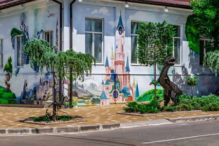 Kherson, Ukraine - July 22, 2020: Park sculptures and fairy-tale paintings on the walls of a kindergarten at the crossroads of Hetmana Sahaidachnoho and Kanatna streets in Kherson. Flowerbeds with metal statues of dinosaurs on the sidewalk of a city streeのeditorial素材