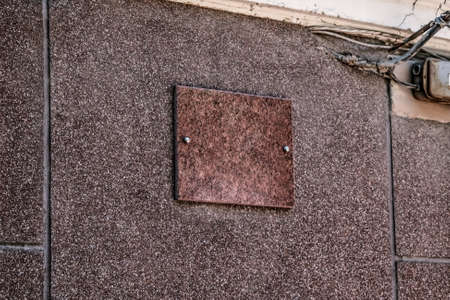 Blank brown granite plaque screwed to the wall with two screws. Real architectural template for text. Background with copy spaceの写真素材