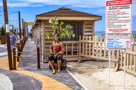 Zaliznyi Port, Ukraine - July 23, 2020: Sculpture of a pirate with a treasure chest on the beach in Zaliznyi Port. Promenade of the Ukrainian resort village on a summer dayのeditorial素材