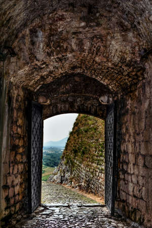 Outward view through the entrance gate of Rozafa Castle in Albania (Shkoder). Ancient stone wall with heavy steel doors, verticalの写真素材