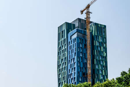 Tirana, Albania - June 21, 2021: Construction crane near the modern Forever Green Tower skyscraper in Tirana. Contemporary Albanian architecture. Background with copy spaceのeditorial素材