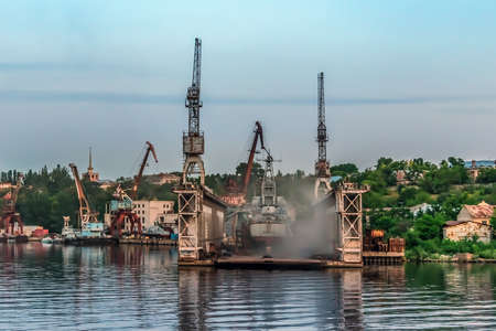 Mykolaiv, Ukraine - July 25, 2020: Smoky repair platform of the Mykolayiv Shipyard on the Inhul River on a summer evening. Open-Air ship repair workshopのeditorial素材