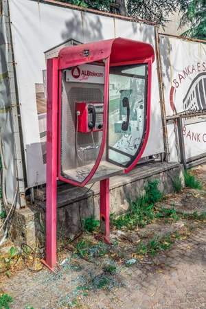 Tirana, Albania - June 21, 2021: An old telephone booth with broken glass on a street in Tirana. Vandals damaged a payphone in the open airのeditorial素材
