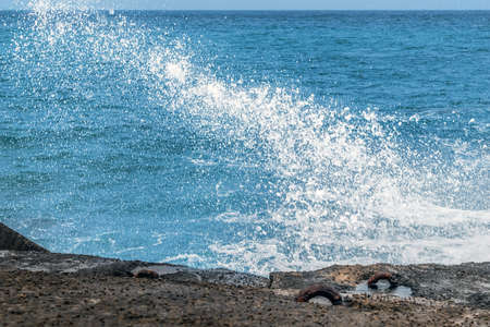 White splashes of a wave crashing against a breakwater. Storm on the sea or oceanの写真素材