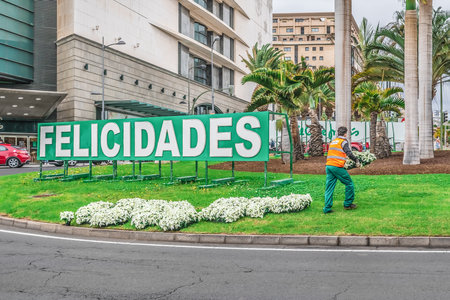 Santa Cruz de Tenerife, Spain - November 25, 2021: A utility worker carries flower pots of poinsettia in a square with sign Felicidades near Intercambiador Sta.Cruz station in Santa Cruzのeditorial素材