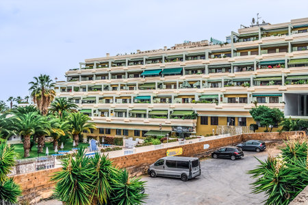 Puerto de la Cruz, Spain - November 25, 2021: Apartamentos Bahia Playa Hotel in Puerto de la Cruz. Parking against the backdrop of a garden with exotic plants and a multistorey building with terracesのeditorial素材