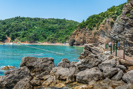 Mogren beach with bright turquoise water among layered rocks in Budva, Montenegro. Beautiful summer tropical landscape with an exotic beach on the Adriatic Seaの写真素材