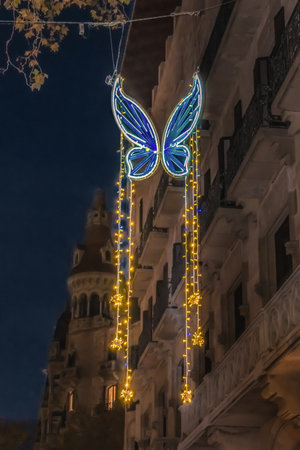 Blue glowing butterfly with garlands on Passeig de Gracia street in Barcelona at night, Spain, vertical. Christmas illumination at dusk outdoorsの写真素材