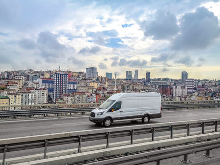 A white van drives fast on a highway against the backdrop of the suburbs of Istanbul, Turkey. Side view of a single car on a city road with a Turkish city backgroundの写真素材