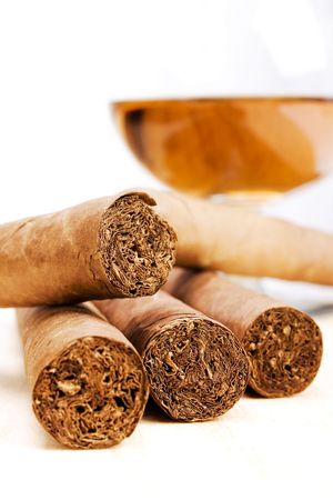 Stock image of Cigars and Cognac over light background, focus on center cigars.の写真素材