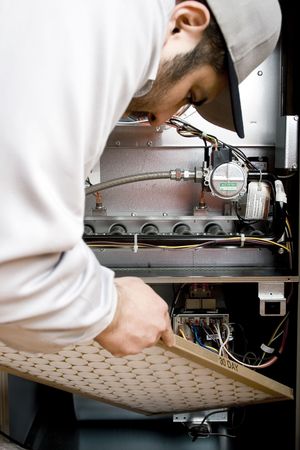 Stock image of HVAC technician replacing filter on furnaceの写真素材
