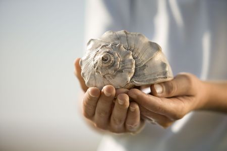 Caucasian pre-teen boy holding seashell.の写真素材