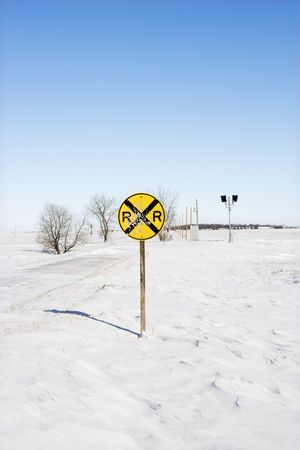 Railroad crossing sign in snow covered rural landscape.の写真素材