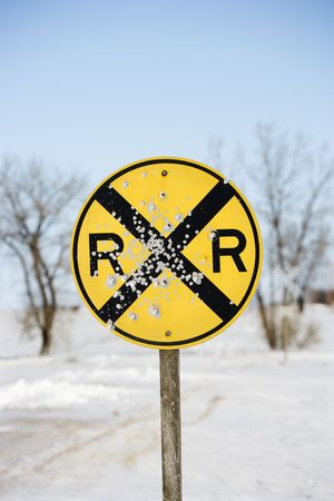 Railroad crossing sign in snow covered rural landscape.の写真素材