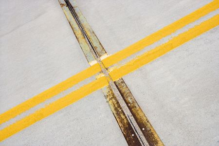Detail of solid double yellow line in road  crossing metal strips in cement.の写真素材