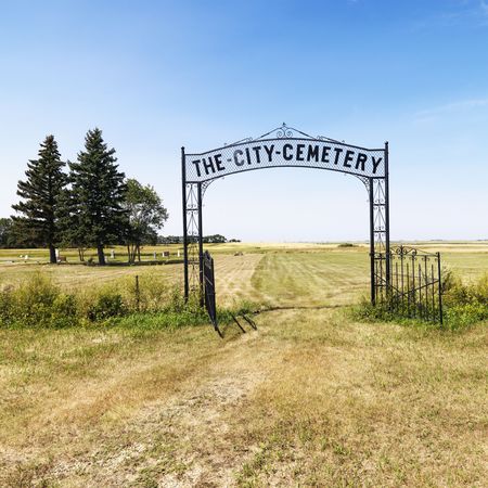 Entrance to rural cemetary in field with decorative iron gate.の写真素材