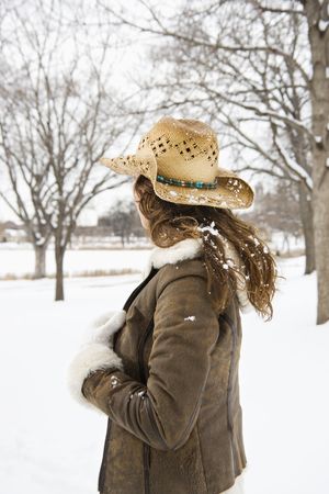 Back view of brunette woman with long hair wearing straw cowboy hat outdoors in the snow.の写真素材