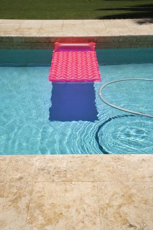 Pink float and vacuum hose in swimming pool.の写真素材