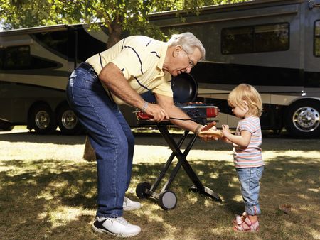 Grandfather giving granddaughter hotdog by RV.の写真素材